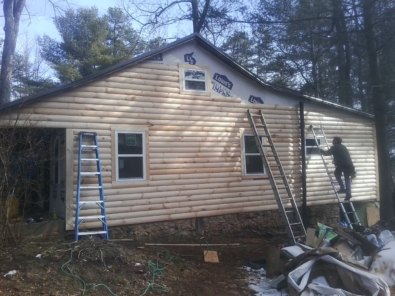 Ladders set against fresh log siding during an exterior remodel in North Olmsted