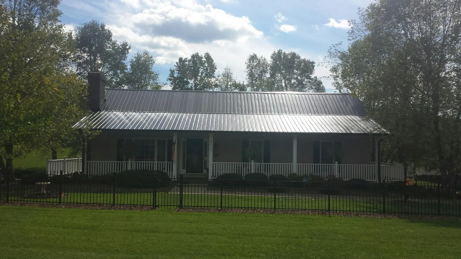 Gray metal roof on a brick ranch with a full width front porch — Gutter Guard Installation work by our crew in North Olmsted