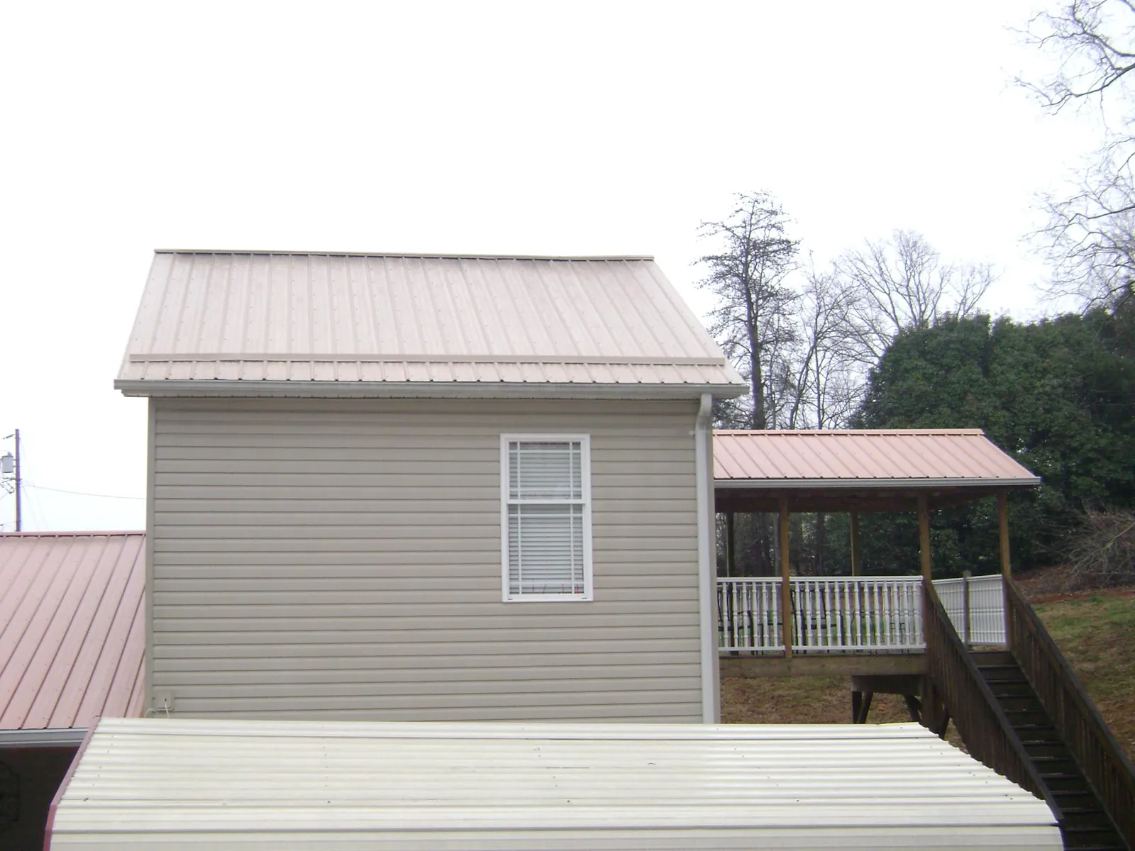 Tan metal roofs on a two story addition and attached porch, from a Roof Replacement job in North Olmsted