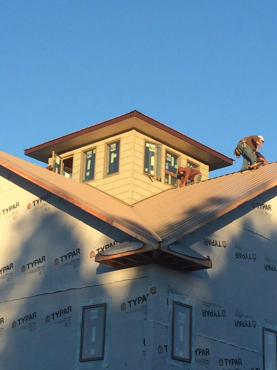 Roofers working around a rooftop cupola on a new metal roof at sunset — Roof Waterproofing in North Olmsted by Roofing Brothers